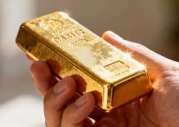 Une main tenant une barre d'or brillante.
