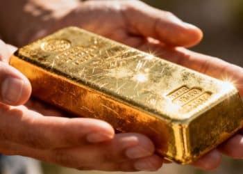 Main d'une personne tenant une barre d'or brillante.