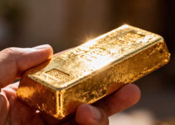 Main d'or tenant une barre d'or brillante.
