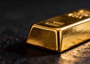 Lingot d'or sur fond sombre, reflets lumineux.