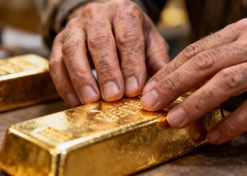Main d'or examinant une barre d'or