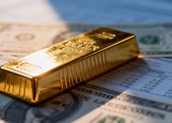 Lingot d'or sur fond flou de documents financiers.