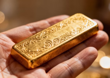 Main d'une personne tenant une barre d'or brillante.
