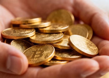 Main d'une personne tenant des pièces d'or brillantes.