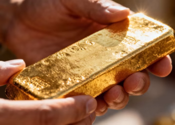 Main d'une personne tenant une barre d'or.