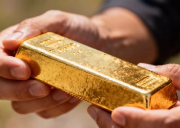 Barre d'or brillant dans une main, investissement pour 2025.