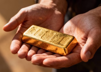 Mains tenant une barre d'or brillante, gros plan.
