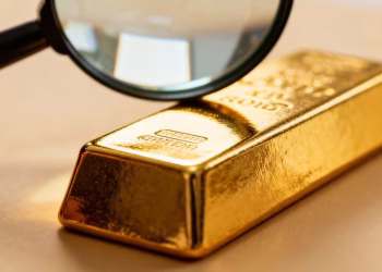 Lingot d'or sous une loupe pour vérifier son authenticité.