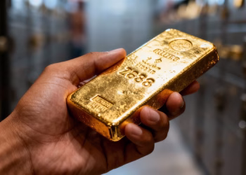 Main d'or tenant une barre d'or pur
