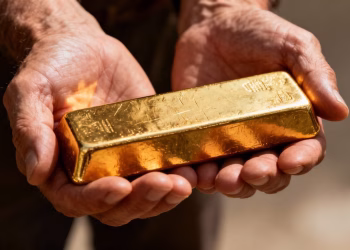 Mains tenant une barre d'or brillante.