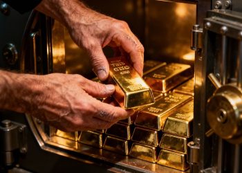 Mains plaçant des lingots d'or dans un coffre-fort.