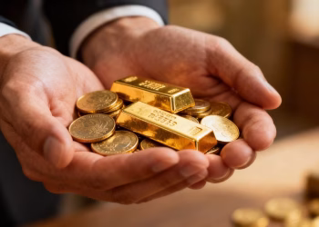 Pièces et lingots d'or dans une main.