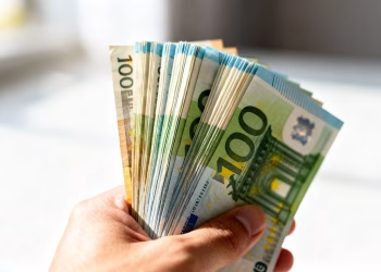 Main d'une personne tenant des billets en euros.