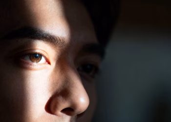 Visage dans l'ombre, un œil éclairé par la lumière.