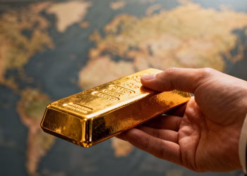 Main d'or tenant une barre d'or brillante.