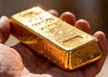 Main dorée tenant une barre d'or brillante.