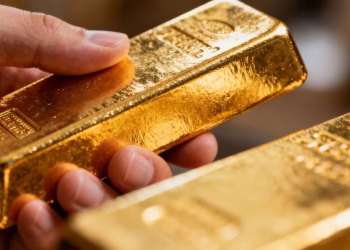 Main dorée tenant une barre d'or brillante.