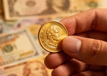 Main d'une personne tenant une pièce d'or.