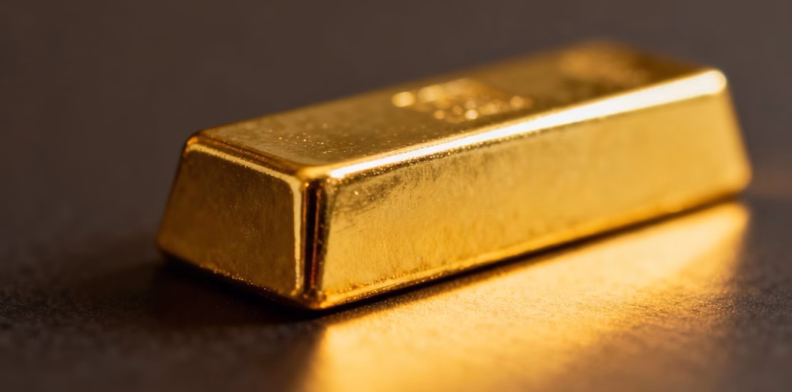 Mini lingot d'or brillant sur fond neutre.
