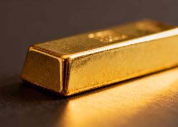 Mini lingot d'or brillant sur fond neutre.