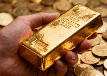 Main d'or tenant une barre d'or avec des pièces.
