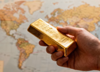 Main d'or tenant une barre d'or avec carte du monde