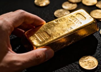 Main d'or tenant une barre d'or avec des pièces.