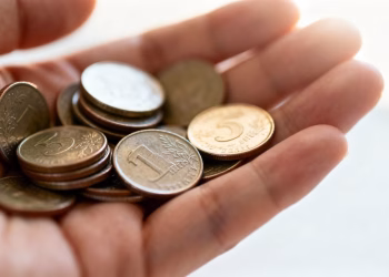 Main d'une personne tenant une petite quantité de pièces.