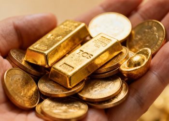 Pièces et lingots d'or dans une main.