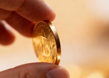 Main d'une personne tenant une pièce d'or.