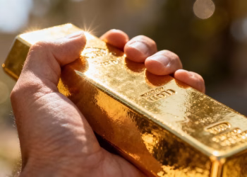 Barre d'or brillant dans une main, symbole de richesse.