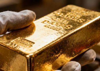 Lingot d'or brillant avec une main le touchant.