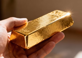 Main d'or tenant une barre d'or brillante.