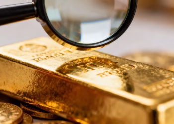 Barre d'or sous une loupe, vérification d'authenticité.