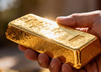 Main d'homme tenant une barre d'or brillante.