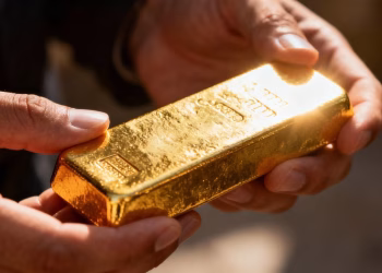Mains tenant une barre d'or brillante.
