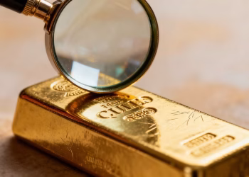 Barre d'or sous une loupe, gros plan.