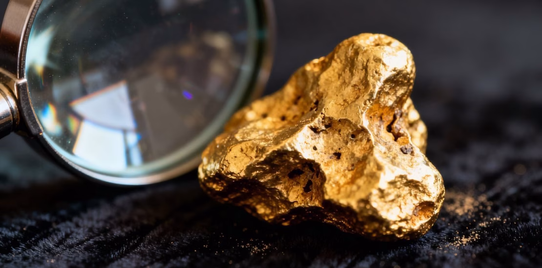 Nugget d'or sous une loupe, mise au point sur le métal.