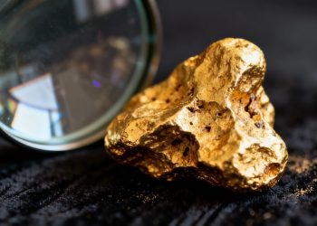 Nugget d'or sous une loupe, mise au point sur le métal.