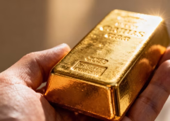 Main d'or tenant une barre d'or brillante.