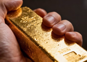 Main d'une personne tenant une barre d'or brillante.