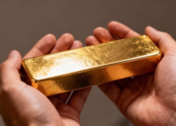 Main d'une personne tenant une barre d'or.