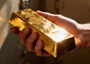 Main d'or tenant une barre d'or brillante.
