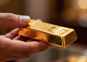 Main d'une personne tenant une barre d'or.