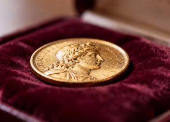 Especialista avaliando uma moeda de ouro numismática para possível herança.