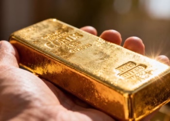 Main d'une personne tenant une barre d'or.