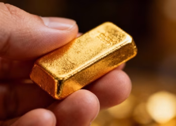 Main d'une personne tenant une barre d'or.