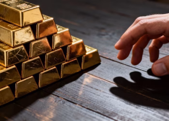 Main tendue vers lingots d'or sur table sombre