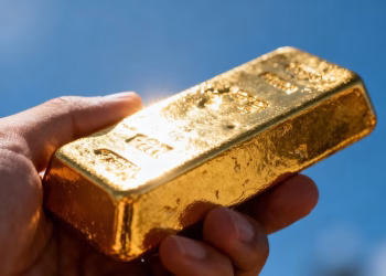 Main d'or tenant une barre d'or brillante.