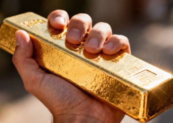 Main d'or tenant une barre d'or brillante.